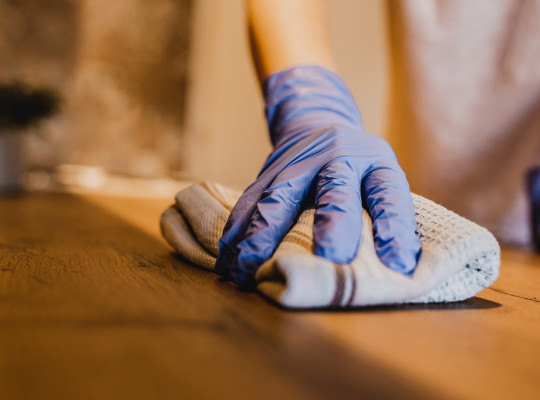 person wearing cleaning glove and wiping down surfaces with a cloth.